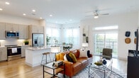 Located in Round Rock, Texas, this thoughtfully designed single-story residence offers a bright, open-concept floor plan with contemporary finishes throughout. Light wood-tone flooring flows seamlessly from the welcoming entry hallway — lined with built-in shelving — into the expansive living and dining areas. The living room is anchored by large windows and a sliding glass door that fills the space with natural light while providing access to an outdoor balcony with scenic views. A ceiling fan adds a practical touch overhead.

The kitchen is well-appointed with shaker-style cabinetry, granite countertops, stainless steel appliances including a French door refrigerator and range, and a breakfast bar island ideal for casual dining. Adjacent to the kitchen, the dining area features generous windows dressed in sheer curtains that invite soft, diffused light.

The bedrooms offer a calm retreat, each featuring plush carpeting, natural light from well-positioned windows, and ample closet space. The bathroom is finished with granite countertops, dual-sink vanity, light cabinetry, and a full tub-shower combination with tile surround. Throughout the residence, crisp white walls and recessed lighting create a clean, modern ambiance that is both functional and inviting.