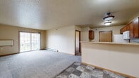 Located at 2411 36th St S in Moorhead, MN, this 2-bedroom, 1-bathroom unit offers a practical and comfortable single-floor layout. The open-concept living and kitchen area serves as the heart of the home, where durable stone-tile flooring transitions into soft carpeting in the living space. The kitchen is well-equipped with warm-toned wood cabinetry, a breakfast bar peninsula, white appliances including a refrigerator, electric range, and microwave, and ample upper cabinet storage. A textured ceiling runs throughout the unit, adding a classic touch to the neutral, beige-toned walls.

The living room receives natural light through a sliding glass door that opens to an outdoor view, complemented by baseboard heating units along the perimeter. Both bedrooms are carpeted and feature natural light from standard windows with outdoor views of the surrounding greenery. The primary bedroom includes a spacious sliding-door closet for ample storage. Each bedroom is connected via a carpeted hallway.

The full bathroom features stone-tile flooring, warm wood vanity cabinetry, a large mirror, a well-lit vanity fixture, and a clean, functional layout. Throughout the unit, wood-tone doors and trim provide a cohesive, understated aesthetic suited for practical everyday living.