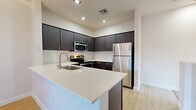 Located at 1601 E Highland Ave in Phoenix, AZ, this multi-level home spans three floors and offers a well-organized layout across its living spaces. The ground level houses an attached garage with an automatic opener and concrete flooring, providing secure and convenient parking. Carpeted staircases with wood handrails connect each floor, creating a smooth flow throughout the home. The main living level features an open-concept kitchen and living area finished with light wood-style flooring. The kitchen is outfitted with dark espresso cabinetry, white quartz countertops, a subway tile backsplash, a stainless steel sink, and a full suite of stainless steel appliances including a refrigerator, range, microwave, and dishwasher. The upper floor is home to two bedrooms, including a generously sized primary bedroom with plush carpeting, dual windows with blinds, and a ceiling fan. A second bedroom features light wood-style flooring, a ceiling fan, crown molding, and sliding glass doors that open to a balcony overlooking the surrounding neighborhood. The full bathroom includes a tub/shower combination, a dark-vanity with white countertop, and tile flooring. A carpeted walk-in closet with wire shelving rounds out the upper level, offering practical storage throughout this thoughtfully designed Phoenix home.