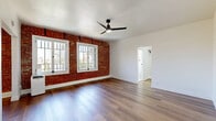 Located at 1775 N Orange Drive in the heart of Hollywood, Los Angeles, this thoughtfully designed unit blends vintage character with modern updates. The open living area serves as the centerpiece of the space, showcasing a striking exposed brick accent wall that spans the length of the room. Multiple white-framed windows allow generous natural light to pour in, offering views of the surrounding neighborhood, while a sleek black ceiling fan adds both style and function overhead. Warm hardwood-style flooring flows continuously throughout, tying the space together cohesively.

The kitchen is well-appointed with white cabinetry, dark countertops, a gas range, stainless steel refrigerator, and a single basin sink — all complemented by a brick-accented window that maintains the unit's distinctive character. A dedicated walk-in closet provides organized shelving and hanging space. The bathroom features classic black-and-white patterned tile flooring, a full soaking tub with shower, and bright white walls, lending a timeless, clean aesthetic. Clean white walls and trim throughout the unit create a bright, neutral backdrop that complements the space's original architectural charm.