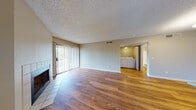 This single-floor residence offers a thoughtfully designed open-concept layout that seamlessly connects the living, dining, and kitchen areas. The living room is anchored by a tiled fireplace and features warm hardwood-style flooring that extends throughout the main areas. Large sliding glass doors with vertical blinds invite natural light and provide access to the outdoors. A dedicated in-unit laundry room with a full-size washer and dryer is conveniently accessible directly from the living area.

The kitchen is well-equipped with stainless steel appliances, including a range, microwave, refrigerator, and dishwasher. White shaker-style cabinetry paired with a subway tile backsplash and light countertops give the kitchen a clean, modern aesthetic. A peninsula with a built-in sink adds additional prep space and storage.

The bedrooms are carpeted for comfort and feature ceiling fans, natural light from windows with outdoor views of greenery, and ample wall space. The bathroom is finished with wood-look flooring, a tub/shower combination, and clean white fixtures throughout.

The textured ceilings are consistent across the unit, and the neutral warm-gray walls provide a versatile backdrop throughout this well-maintained and move-in-ready residence.