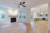 Located on Bainbridge Island, WA, this well-appointed single-floor home offers three bedrooms, two bathrooms, and a thoughtfully designed layout. The open living room is a standout space, featuring light hardwood flooring, a ceiling fan, and a classic tile-surround fireplace with a dark wood mantel as its focal point. A bay window arrangement floods the room with natural light and offers views of the surrounding greenery, while the space flows seamlessly into the kitchen. The kitchen is outfitted with gray shaker-style cabinetry, white quartz countertops, a subway tile backsplash, stainless steel appliances, and a pendant chandelier, combining both style and functionality. The bedrooms are carpeted for comfort, with the secondary bedrooms offering multiple windows that bring in ample natural light and outdoor views. The primary bedroom includes access to a dedicated closet and a private bathroom. Both bathrooms are finished with large-format white tile flooring, gray vanity cabinetry, and clean, modern fixtures. Additional closets throughout the home provide generous storage. The consistent use of white walls, light wood floors, and black hardware accents creates a cohesive, modern aesthetic throughout.