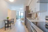 Located at 1430 Highland Rd W in Kitchener, Ontario, this well-designed 2-bedroom, 1-bathroom unit offers a smart and functional layout across a single floor. Light-toned hardwood flooring runs throughout the main living areas, lending a clean and cohesive aesthetic.

The galley-style kitchen is thoughtfully appointed with two-tone cabinetry — combining crisp white upper cabinets with warm wood-finish lower cabinets — complemented by a white subway tile backsplash, light quartz countertops, and stainless steel appliances including a refrigerator, dishwasher, and range. A compact dining area sits adjacent, ideal for everyday meals.

The living room is a standout feature, anchored by floor-to-ceiling windows and a glass door that opens onto a private balcony, offering sweeping views of the Kitchener skyline and filling the space with abundant natural light.

Both bedrooms are finished with plush carpeting and feature large windows. The primary bedroom benefits from an elevated city view through a generous floor-to-ceiling window, while both rooms include sliding closets for practical storage.

The bathroom is finished with neutral tile surrounds and includes a full soaker tub with shower. Clean white walls and consistent finishes throughout give the entire unit a modern, move-in-ready appeal.