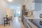 Located at 1430 Highland Rd W in Kitchener, Ontario, this well-designed 2-bedroom, 1-bathroom unit offers a smart and functional layout across a single floor. Light-toned hardwood flooring runs throughout the main living areas, lending a clean and cohesive aesthetic.

The galley-style kitchen is thoughtfully appointed with two-tone cabinetry — combining crisp white upper cabinets with warm wood-finish lower cabinets — complemented by a white subway tile backsplash, light quartz countertops, and stainless steel appliances including a refrigerator, dishwasher, and range. A compact dining area sits adjacent, ideal for everyday meals.

The living room is a standout feature, anchored by floor-to-ceiling windows and a glass door that opens onto a private balcony, offering sweeping views of the Kitchener skyline and filling the space with abundant natural light.

Both bedrooms are finished with plush carpeting and feature large windows. The primary bedroom benefits from an elevated city view through a generous floor-to-ceiling window, while both rooms include sliding closets for practical storage.

The bathroom is finished with neutral tile surrounds and includes a full soaker tub with shower. Clean white walls and consistent finishes throughout give the entire unit a modern, move-in-ready appeal.