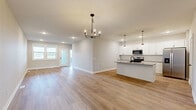 Located in Lakeville, MN, this two-story home offers four bedrooms, three bathrooms, and a well-organized layout spread across two generously sized floors. The main level features an open-concept kitchen and living area with light hardwood-style flooring, white shaker cabinetry, a central island with a dark countertop and undermount sink, stainless steel appliances, and modern pendant lighting — all contributing to a clean, contemporary aesthetic. An adjacent dining area is accented by a striking black chandelier. The upper level houses the primary bedroom suite, which includes a private en-suite bathroom featuring light wood-look flooring, a glass-enclosed shower with black-framed doors, and access to a walk-in closet outfitted with wire shelving systems. Additional bedrooms are carpeted and bright, with windows that bring in natural light and views of the surrounding neighborhood. Bathrooms throughout maintain a consistent modern style with white vanities and recessed lighting. The attached garage provides functional utility space with a concrete floor and electrical panel access. A hallway, pantry, and utility room round out the practical offerings of this home. Outside, a deck overlooks open greenspace within a developing community, offering a pleasant outdoor setting.