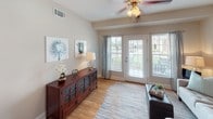 Located in Tega Cay, South Carolina, this single-floor residence offers a thoughtfully designed layout with a warm, cohesive aesthetic throughout. The kitchen is a standout feature, showcasing rich dark cherry cabinetry, granite countertops, a double-basin stainless steel sink, and black appliances including a gas range, microwave, and refrigerator. Pendant lighting adds a polished touch, while an in-unit laundry area is conveniently situated nearby. The living area is bright and welcoming, featuring hardwood-style flooring, a ceiling fan, and French doors that open to an outdoor space, allowing natural light to flow freely. The bedrooms are carpeted for comfort and include generous closet space — one featuring a spacious walk-in closet outfitted with wire shelving and hanging rods. The primary bathroom is well-equipped with a double vanity featuring dark cabinetry, a soaking tub, a separate shower, and tile flooring. A secondary bathroom mirrors the same quality, with a tub-shower combination and a single-sink vanity. Neutral wall tones and clean finishes are consistent throughout, creating a calm and inviting atmosphere across every room of this Tega Cay home.