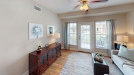 Located in Tega Cay, South Carolina, this single-floor residence offers a thoughtfully designed layout with a warm, cohesive aesthetic throughout. The kitchen is a standout feature, showcasing rich dark cherry cabinetry, granite countertops, a double-basin stainless steel sink, and black appliances including a gas range, microwave, and refrigerator. Pendant lighting adds a polished touch, while an in-unit laundry area is conveniently situated nearby. The living area is bright and welcoming, featuring hardwood-style flooring, a ceiling fan, and French doors that open to an outdoor space, allowing natural light to flow freely. The bedrooms are carpeted for comfort and include generous closet space — one featuring a spacious walk-in closet outfitted with wire shelving and hanging rods. The primary bathroom is well-equipped with a double vanity featuring dark cabinetry, a soaking tub, a separate shower, and tile flooring. A secondary bathroom mirrors the same quality, with a tub-shower combination and a single-sink vanity. Neutral wall tones and clean finishes are consistent throughout, creating a calm and inviting atmosphere across every room of this Tega Cay home.