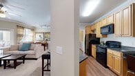 Located at 1810 Arden Creek Pl in Charlottesville, VA, this single-story residence offers two bedrooms and two bathrooms within a thoughtfully designed floor plan. The open-concept kitchen is outfitted with light maple cabinetry, dark granite countertops, a breakfast bar peninsula, and black appliances including a refrigerator, range, and built-in microwave, all set atop warm hardwood-style flooring. Crown molding throughout adds a refined architectural detail.

The living room is bright and welcoming, featuring plush carpeting, a ceiling fan, crown molding, and a glass door that invites natural light and outdoor access. The primary bedroom is generously sized, with soft carpet, large windows, and ample room for a full suite of furniture. The second bedroom is equally comfortable, also carpeted and well-lit with a window. Both bathrooms are finished with tile flooring, wood-toned vanities, and extended countertops providing useful storage.

A dedicated laundry room houses a full-size side-by-side washer and dryer, adding everyday convenience. Two closets, a hallway, and an efficient layout complete this functional and comfortable single-floor home.