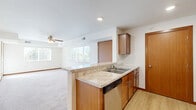This one-bedroom, one-bathroom residence at 2601 Jefferson Rd in Northfield, MN offers a functional and comfortable layout across a single floor. The open-concept kitchen is a standout feature, equipped with stainless steel appliances including a refrigerator, range, and microwave, complemented by warm wood cabinetry, light stone-look countertops, a built-in dishwasher, and a peninsula that connects seamlessly to the living area. The kitchen also benefits from hardwood-style flooring and a pantry for additional storage. The living room is generously sized, bathed in natural light from multiple windows, and features plush carpeting and a ceiling fan. A private balcony extends the living space outdoors. The bedroom offers comfortable proportions, carpet flooring, a large sliding-door closet, and a bright window with outdoor views. An additional closet provides further storage convenience. The bathroom includes a full tub-shower combination with clean white finishes. A dedicated utility room completes the layout. Bold red-toned baseboards and warm wood door accents throughout lend the space a cohesive, welcoming character.