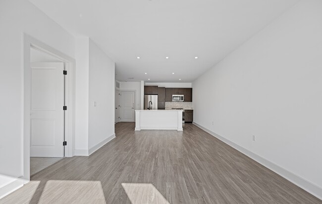 Empty, the main room shows its full depth from the bedroom door to the kitchen. - The Landing at Vinnin Square