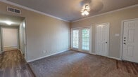 This single-story home offers a thoughtfully designed layout with a warm, neutral color palette throughout. The living area is generously sized, featuring plush carpeting, elegant crown molding, a ceiling fan with light fixture, and French doors that invite natural light and provide access to the outdoors. The open, airy ambiance is further enhanced by the soft, earthy tones of the walls and the clean white trim detailing.

The galley-style kitchen is efficiently arranged with light wood cabinetry, granite-look countertops, wood-look flooring, and a full suite of stainless steel appliances including a refrigerator, gas range, built-in microwave, and dishwasher. A dedicated entryway door provides convenient access directly from the kitchen area.

The bedrooms are carpeted and well-lit, each featuring ceiling fans and windows that bring in natural light with views of the surrounding greenery. The rooms offer a calm, neutral atmosphere suitable for restful living.

Two full bathrooms serve the home, each with wood-look flooring, a tub-shower combination with tiled surround, a vanity with ample cabinet storage, and a large mirror. The bathrooms are clean and functional, with a consistent design aesthetic that complements the rest of the home.