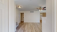 This well-appointed two-story home offers 2 bedrooms and 2 bathrooms across two thoughtfully laid-out floors. The main level encompasses an open-plan living, dining, and kitchen area, complemented by an entrance, a hallway, and a full bathroom. Light-toned hardwood-style flooring runs throughout the main level, enhancing the bright, airy atmosphere. The living room is anchored by a fireplace with a clean white surround and features a ceiling fan with integrated lighting. Sliding glass doors allow natural light to fill the space and provide outdoor access. Adjacent to the living area, the dining space is highlighted by an elegant brass chandelier. The kitchen is equipped with gray shaker-style cabinetry, dark granite countertops, and stainless steel appliances including a range, dishwasher, and refrigerator. A carpeted staircase leads to the upper floor, where both bedrooms are located. Each bedroom is fitted with a ceiling fan, plush carpet flooring, and ample natural light. The generously sized primary bedroom offers considerable space for a full furniture arrangement. A closet and a second bathroom round out the upper level. Ceiling fans are present throughout both floors, ensuring consistent comfort across the entire home.