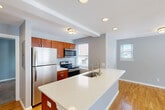 Located at 3838 Park Ave in St. Louis, MO, this two-bedroom, one-bathroom unit offers a well-designed single-floor layout that makes efficient use of its space. The open-concept kitchen and living area serves as the heart of the home, featuring warm hardwood flooring, a large quartz-topped peninsula with an undermount sink, and rich cherry wood cabinetry. Stainless steel appliances — including a refrigerator, electric range, and microwave — complete the kitchen. Multiple windows flood the living area with natural light, enhancing the open feel of the space.

Both bedrooms are carpeted and painted in soft gray tones, each equipped with ceiling fans and windows with blinds. The secondary bedroom features hardwood flooring, while the primary bedroom offers a more intimate feel with plush carpet. Two closets provide ample storage throughout the unit.

The bathroom includes a full tub-shower combination with neutral tile surround, offering a clean and functional design. A dedicated laundry area adds everyday convenience. The overall aesthetic is modern and understated, with consistent gray walls, white trim, and warm wood flooring tying the space together cohesively.