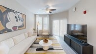 Located at 4595 Huntsman Dr in Kissimmee, FL, this well-appointed one-bedroom, one-bathroom residence offers a smartly laid-out single-floor plan designed for comfortable, efficient living. The open-concept kitchen and living area form the heart of the home, with the kitchen showcasing crisp white shaker cabinetry, granite-style countertops, and a full suite of stainless steel appliances including a range, over-the-range microwave, dishwasher, and refrigerator. Light wood-look flooring and track lighting enhance the clean, modern aesthetic. The living room is bright and inviting, featuring a ceiling fan, large windows with blinds and curtains, and a sliding glass door that allows generous natural light to fill the space. The bedroom is a comfortable retreat finished with plush carpet, a ceiling fan, dual windows dressed in white curtains, and ample room for a full furniture arrangement. A dedicated closet provides convenient storage. The bathroom is clean and functional, featuring a tiled shower-tub combination with a curved curtain rod, wood-look flooring, and neutral wall tones that contribute to an overall calming atmosphere throughout the home.