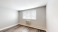 This one-bedroom, one-bathroom unit at 2800 Axe Factory Rd in Philadelphia, PA offers a thoughtfully laid-out single-floor residence with a clean, modern aesthetic throughout. Hardwood-style flooring runs consistently across the living spaces, complementing the neutral gray tones of the walls and crisp white trim and baseboards.

The kitchen is well-appointed with warm wood cabinetry extending to the ceiling for generous storage, a stainless steel refrigerator, gas range, and built-in microwave, along with a blue tile backsplash that adds a touch of character. Flush overhead lighting keeps the space bright and functional.

The bedroom features a ceiling fan with light fixture, a wide window fitted with blinds that allows natural light to fill the room, a built-in closet with panel doors, and a wall-mounted air conditioning unit with baseboard heating for year-round comfort. In total, the unit includes three closets, providing notable storage capacity.

The bathroom is finished with clean white tile surrounding the tub-shower combination, accented by a striking black-and-white mosaic border tile, giving it a polished, contemporary look. A hallway connects the rooms, contributing to a practical and efficient floor plan. Overall, this unit presents a tidy, move-in-ready living space in Northeast Philadelphia.