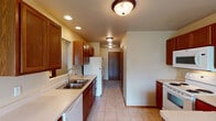This single-floor residence offers a well-organized layout designed for comfortable everyday living. The galley-style kitchen is equipped with rich oak cabinetry, light countertops, a double stainless steel sink, and a full suite of white appliances including a refrigerator, range, microwave, and dishwasher. Recessed and flush-mount ceiling lighting illuminates the tile flooring throughout the kitchen and hallway, which leads to the main living areas.

The spacious living room features neutral carpet, warm beige walls, a baseboard heating system, and a fireplace framed by a wood mantel and tile surround, serving as a focal point of the room. An adjacent dining area benefits from a sliding glass door that allows natural light in, complemented by a classic chandelier overhead. A pass-through opening connects the dining space visually to the kitchen.

The unit includes two bathrooms: a full bathroom with a glass-enclosed stand-up shower, a single-sink vanity with oak cabinetry, and tile flooring, and a half bathroom with a vanity and toilet. The bedrooms are carpeted, each featuring windows with outdoor views and baseboard heating, providing comfortable, naturally lit spaces. Overall, the unit offers a functional and cohesive design throughout.