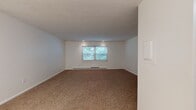 This single-floor, one-bedroom, one-bathroom unit at 140 Anton St in Bridgeport, Connecticut offers a straightforward and functional layout. The spacious living area features warm, neutral-toned carpet and crisp white walls, creating a clean and open atmosphere. A centrally positioned window allows natural light to filter in, offering views of surrounding greenery, while baseboard heating units provide practical warmth throughout. Recessed lighting adds to the well-lit character of the space.

The living area flows openly toward the kitchen, which transitions to tile flooring and is equipped with wood-toned cabinetry, ample upper and lower storage, a double-basin sink, an electric range, and a full-size refrigerator. A range hood above the stove adds functionality to this compact but well-organized cooking space.

The bedroom features wood-style laminate flooring, a window with outdoor greenery views, baseboard heating, and two bifold closets offering generous built-in storage with shelving and hanging rods. The full bathroom includes a clean white tub and shower combination with tiled surround and chrome fixtures. Overall, the unit presents a tidy, move-in-ready environment suitable for practical everyday living.