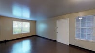 This single-floor, 3-bedroom, 2-bathroom unit offers a practical and well-organized layout designed to maximize functionality. The spacious living area features durable, polished tile flooring, neutral-toned walls, and multiple windows that allow natural light to fill the space while providing views of surrounding greenery. The entry opens directly into this generous living space, which benefits from two windows and a clean, open feel.

The galley-style kitchen is efficiently designed with warm wood cabinetry lining both sides, laminate countertops, a double-basin sink, and white appliances including a gas range, dishwasher, and refrigerator. Durable vinyl flooring runs the length of the kitchen, and a door at the far end provides additional access.

Each of the three bedrooms is a comfortable size, featuring neutral walls, dark baseboards, and individual windows overlooking outdoor greenery. One bedroom features plush carpeting, while the others have the same durable tile flooring found throughout the unit.

The two bathrooms are functionally appointed. The full bathroom includes a shower-tub combination, while the second bathroom features a vanity with a wood-framed medicine cabinet mirror, white fixtures, and tiled walls. Both bathrooms maintain a clean, utilitarian aesthetic consistent with the rest of the unit.