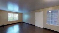 This single-floor, 3-bedroom, 2-bathroom unit offers a practical and well-organized layout designed to maximize functionality. The spacious living area features durable, polished tile flooring, neutral-toned walls, and multiple windows that allow natural light to fill the space while providing views of surrounding greenery. The entry opens directly into this generous living space, which benefits from two windows and a clean, open feel.

The galley-style kitchen is efficiently designed with warm wood cabinetry lining both sides, laminate countertops, a double-basin sink, and white appliances including a gas range, dishwasher, and refrigerator. Durable vinyl flooring runs the length of the kitchen, and a door at the far end provides additional access.

Each of the three bedrooms is a comfortable size, featuring neutral walls, dark baseboards, and individual windows overlooking outdoor greenery. One bedroom features plush carpeting, while the others have the same durable tile flooring found throughout the unit.

The two bathrooms are functionally appointed. The full bathroom includes a shower-tub combination, while the second bathroom features a vanity with a wood-framed medicine cabinet mirror, white fixtures, and tiled walls. Both bathrooms maintain a clean, utilitarian aesthetic consistent with the rest of the unit.
