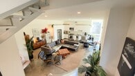 This modern two-bedroom, two-bathroom condominium spans 1,160 square feet across two thoughtfully designed floors in West Los Angeles. The ground floor (520 sq ft) features an open-concept living room and kitchen, showcasing polished concrete floors, recessed lighting, and crisp white walls that create a clean, minimalist aesthetic. The kitchen is equipped with sleek white cabinetry and a stainless steel French door refrigerator. A contemporary staircase with metal railings connects the floors, serving as a striking architectural focal point. The upper floor (640 sq ft) hosts both bedrooms, including a spacious 220 sq ft primary bedroom with light hardwood flooring, large windows, and access to outdoor views. The second bedroom also features hardwood floors and ample natural light. The primary bathroom offers a double-sink vanity with a large mirror, modern white cabinetry, and a glass-enclosed shower. The secondary bathroom includes a full tub-shower combination with textured tile surround. A standout feature is the expansive private rooftop deck with open sky views and room for outdoor entertaining, completing this stylish urban residence.
