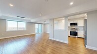 Located at 925 Mix Ave in Hamden, Connecticut, this well-appointed 2-bedroom, 2-bathroom residence offers a thoughtfully designed single-level layout with a clean, modern aesthetic throughout. Warm hardwood-style flooring flows seamlessly across every room, complemented by neutral gray walls and crisp white trim that create a bright, cohesive atmosphere.

The open-concept living area is generously proportioned, featuring recessed lighting and a sliding glass door that invites natural light and provides access to an outdoor balcony. The layout connects fluidly to the kitchen, which is equipped with stainless steel appliances including a range, microwave hood, and refrigerator, all set against white shaker-style cabinetry and elegant stone countertops with subtle veining.

The spacious primary bedroom offers scenic views of the surrounding landscape through large sliding windows, bringing in abundant natural light. A wall-mounted mini-split unit provides efficient climate control. The second bedroom is similarly well-lit and comfortable. Both bathrooms are finished in a clean, minimalist style, with one featuring a full soaking tub and shower surround. A hallway and dedicated closet provide convenient storage. Recessed lighting throughout the home ensures a consistently bright and welcoming environment.