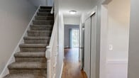 Located at 35 Arbor Way in Ellington, CT, this two-floor home offers a thoughtful layout spread across two levels. The main floor features warm hardwood flooring throughout, a carpeted staircase with white-painted banisters, and a bright hallway that leads naturally into the living spaces. The kitchen is well-equipped with oak cabinetry, granite-style countertops, and white appliances, opening toward a dining area with a ceiling fan, chair-rail wainscoting, and a large window overlooking the greenery outside. The living area is a standout, boasting soaring vaulted ceilings, hardwood floors, and a sliding glass door that floods the room with natural light and provides access to an outdoor patio surrounded by lush trees. A pantry, laundry area, and two closets add practical storage on the main level. Upstairs, the generously sized bedroom features plush carpet, soft neutral tones, a sliding-door closet, and access to a full bathroom. A second bathroom on the main floor includes tiled walls and a walk-in shower. The two-bathroom configuration, multi-level design, and abundant natural light throughout make this a well-rounded and comfortable home in a serene Connecticut setting.