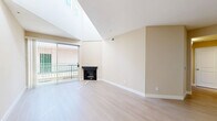 Located at 10621 Valley Spring Lane in the North Hollywood neighborhood of Los Angeles, this one-bedroom, one-bathroom residence offers a thoughtfully designed single-level layout. The open-concept living and dining area is a standout feature, showcasing light wood-tone flooring, warm neutral wall tones, and a striking elevated ceiling line that enhances the sense of volume and airiness. A classic fireplace anchors the living room, while sliding glass doors lead to a private balcony, allowing natural light to pour into the space. The kitchen is efficiently laid out in a galley style, featuring warm wood cabinetry, stone-look countertops, and stainless steel appliances including a gas range and built-in microwave. A pass-through window connects the kitchen to the dining area for easy functionality. The bedroom is carpeted for comfort and includes dual mirrored sliding-door closets, vaulted ceiling detail, and a window that brings in natural light. The bathroom features a long vanity with dual sinks, white cabinetry, and a glass-panel shower enclosure. A hallway connects the bedroom and bathroom, with two closets providing ample additional storage throughout the unit.