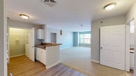 This two-bedroom, three-bathroom residence at 80 Ferry St in Middletown, CT offers a thoughtfully arranged single-floor layout. The open-concept kitchen and living area forms the heart of the home, where white cabinetry, dark granite-style countertops, and a peninsula with a sink create a functional and cohesive space. White appliances including a gas range and refrigerator complement the kitchen's clean aesthetic, while hardwood-style flooring flows underfoot. The living area extends naturally from the kitchen, bathed in natural light from a large window with outdoor views of the surrounding neighborhood. Both bedrooms are carpeted and well-proportioned, each featuring ample closet space with double doors. The primary bedroom offers generous room to furnish comfortably. The three bathrooms include light wood-style flooring, white vanities with dark countertops, mirrors, and tub/shower combinations, with grab bars featured in at least one bath. A dedicated in-unit laundry room with wire shelving and a full-size washer hookup adds everyday convenience. Soft gray-blue walls throughout lend the space a calm, neutral ambiance, while consistent trim and paneled doors provide a cohesive finish across all rooms.