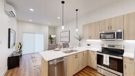 This well-designed one-bedroom, one-bathroom unit offers a thoughtful layout that maximizes every square foot with clean lines and modern finishes. The open-concept kitchen and living area serves as the heart of the space, featuring light wood-tone cabinetry with matte black hardware, crisp white quartz countertops, and a full suite of stainless steel appliances including a French door refrigerator, electric range, over-the-range microwave, and dishwasher. A peninsula with seating provides a casual dining option while maintaining a seamless flow into the living area. The living room is bright and airy, highlighted by large sliding doors that allow natural light to fill the space, along with recessed lighting and warm wood-look plank flooring throughout. The bedroom offers a comfortable and private retreat, featuring plush carpet flooring, multiple windows with roller shades, and a spacious closet. The bathroom is finished with the same light wood-tone vanity cabinetry, white countertops, and wood-look flooring, complemented by a full tub and shower combination. A consistent neutral color palette and cohesive design language throughout give this unit a polished, contemporary feel.
