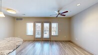 Located in Kansas City, MO, this two-bedroom, three-bathroom two-story residence offers a well-designed layout spread across two comfortable floors. The main level features an open-concept kitchen and living area highlighted by light wood-look flooring and abundant natural light. The kitchen is outfitted with rich dark-toned cabinetry, stainless steel appliances, a subway tile backsplash, pendant lighting, and a granite-topped island that doubles as a breakfast bar. The living area flows naturally from the kitchen and opens to a private balcony through glass doors flanked by large windows, allowing generous natural light and outdoor views. Ceiling fans are present throughout the home for added comfort. The upper level houses both bedrooms, each carpeted and fitted with ceiling fans. The generously sized primary bedroom connects directly to its own bathroom, offering a private retreat. The bathrooms are finished with granite-topped dark wood vanities and frameless sliding glass shower enclosures with tile surrounds and built-in bench seating. Two closets provide practical storage solutions. The clean, neutral color palette and modern finishes throughout create a cohesive and welcoming ambiance across the entire home.