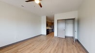 This single-floor studio unit in Louisville's 40206 zip code offers a well-designed, open layout finished with light hardwood-style flooring and clean white walls throughout. The living area is generously proportioned, benefiting from multiple windows that admit natural light, an exterior-facing door, and a ceiling fan that enhances airflow and comfort. The open flow of the space connects the living area to the kitchen corridor seamlessly.

The kitchen is outfitted with warm-toned cabinetry, a herringbone-patterned tile backsplash, light countertops, and a full suite of black appliances including a gas range, microwave, and refrigerator. A hallway connects the kitchen to additional utility areas, where an in-unit washer is tucked alongside a closet with built-in shelving, providing practical storage solutions.

The full bathroom features a soaking tub with a tiled surround in white subway tile, accented by matte black fixtures for a contemporary finish. Light tile flooring completes the clean, modern aesthetic of the space. Throughout the unit, dark baseboards provide a subtle contrast to the neutral palette, lending the interior a cohesive, well-considered design.