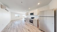 Located at 231 N 11th St in Las Vegas, NV, this thoughtfully designed single-floor unit offers a clean, modern aesthetic throughout. Light wood-tone flooring runs continuously across the entire space, complementing the crisp white walls and creating a bright, cohesive feel.

The open-concept layout seamlessly connects the living area and kitchen, maximizing the sense of space. The kitchen is outfitted with stainless steel appliances, including a full-size refrigerator, electric range, and over-the-range microwave. Two-tone cabinetry — white upper cabinets paired with light wood lower cabinets — adds visual depth, while white countertops keep the look fresh and functional.

The living area is flooded with natural light through a large window fitted with blinds and a sliding glass door that opens to a private balcony, offering views of the Las Vegas skyline. A wall-mounted mini-split unit provides climate control. Recessed lighting throughout ensures well-lit interiors at any hour.

The unit also includes a dedicated storage closet with wire shelving and additional hanging space, offering practical organization solutions. A keypad-secured entry door adds a layer of convenience and security. The bathroom and all rooms maintain the same clean, minimalist design language found throughout the rest of the space.
