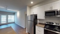 Located at 910 3rd Ave in Chula Vista, this ground-floor unit offers a thoughtfully designed single-level layout with contemporary finishes throughout. The kitchen is a standout feature, equipped with stainless steel appliances including a refrigerator, electric range, and over-the-range microwave. Crisp white shaker-style cabinetry provides ample storage, complemented by neutral-toned countertops and a undermount sink. Wood-look luxury vinyl plank flooring runs through the kitchen and living areas, adding warmth and durability.

The living area is bright and open, benefiting from natural light through large windows and a glass door that leads to an outdoor space, offering views of the exterior surroundings. Track lighting adds a modern touch overhead. Bedrooms feature plush carpeting and neutral gray walls, creating a calm atmosphere. The primary bedroom includes access to a walk-in closet with built-in shelving, along with a separate door leading to additional space. Bathrooms are finished with clean white tile surrounds, tub and shower combinations, and chrome fixtures, maintaining a consistent, modern aesthetic throughout the unit.