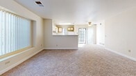 Located at 7929 W Mansfield Pkwy in Lakewood, Colorado, this single-floor, two-bedroom, two-bathroom unit offers a functional and straightforward layout. The open-concept living and kitchen area serves as the heart of the space, where a peninsula counter with a built-in sink visually connects the kitchen to the living room. The kitchen features wood-toned cabinetry with white cabinet fronts, a light-toned countertop, white appliances including a range, microwave, and refrigerator, and hardwood-style flooring. The living area extends comfortably beyond the peninsula, finished with neutral carpet and illuminated by a large multi-pane window and a glass patio door that invites natural light. Both bedrooms are carpeted and feature large windows that bring in views of surrounding greenery. The primary bedroom includes a built-in closet. The two bathrooms each feature wood-toned vanity cabinetry, light countertops, hardwood-style flooring, and a tiled tub-shower combination with neutral taupe tile. Throughout, the unit maintains a consistent neutral color palette of warm beige tones, creating a cohesive and understated ambiance.