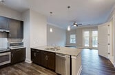 This contemporary 710 square foot apartment offers a harmonious blend of style and functionality. The open-concept layout seamlessly integrates the kitchen, living, and dining areas, creating a spacious feel. The kitchen boasts dark wood cabinetry, stainless steel appliances, and a sleek tile backsplash, complemented by a granite-topped island perfect for casual dining or meal preparation.

The living area is flooded with natural light from large windows and a glass door leading to a balcony, offering pleasant outdoor views. Hardwood flooring extends throughout the main living spaces, adding warmth and continuity. The bedroom, measuring 160 square feet, features plush carpeting and ample closet space with built-in wire shelving systems.

The bathroom is well-appointed with a granite-topped vanity, large mirror, and a tub-shower combination equipped with multiple grab bars for safety and convenience. Additional amenities include a ceiling fan in the living area, roller shades on windows, and recessed lighting throughout. This apartment combines modern design with practical features, creating an inviting and efficient living space.
