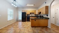 Located at 9010 Betel Dr in El Paso, Texas, this single-story, 2-bedroom, 1-bathroom home offers a well-organized layout designed for comfortable everyday living. The combined kitchen and dining area serves as the heart of the home, featuring warm honey-toned wood cabinetry, dark granite countertops, a mosaic tile backsplash, black appliances including a full-size refrigerator, dishwasher, and range, and a central kitchen island with additional counter space. Large terracotta-style floor tiles extend throughout the kitchen and dining area, complemented by a pendant light fixture that adds a modern touch. An elegant arched doorway connects the kitchen to the rest of the home. The living room is accessible from the main living area and is equipped with a ceiling fan. Both bedrooms are carpeted and feature ceiling fans, neutral-toned walls, and window blinds that allow for natural light. The primary bedroom includes a walk-in closet with built-in shelving, while additional closets provide ample storage throughout. The full bathroom offers a tub/shower combination with tile surround, dark fixture hardware, a wood vanity with granite countertop, and matching tile flooring. A private patio completes this home's functional and cohesive design.