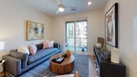 This thoughtfully designed two-bedroom, two-bathroom residence delivers a clean, contemporary aesthetic throughout its single-floor layout. The open-concept kitchen is a standout feature, outfitted with crisp white shaker cabinetry, quartz countertops, a large center island, and a full suite of stainless steel appliances including a French door refrigerator, dishwasher, built-in microwave, and range. Recessed and linear lighting illuminates the space, complementing the warm wood-tone flooring that flows throughout the unit. The living area is bright and welcoming, anchored by a sliding glass door that opens to a private balcony, bringing in natural light and outdoor views. Both bedrooms are comfortably sized, featuring ceiling fans, neutral tones, and wood-look flooring. The primary bedroom connects to an en-suite bathroom with a dual-sink vanity, white cabinetry, and a well-appointed walk-in closet. The second bathroom includes a full soaking tub with shower, a single-sink vanity, and an adjacent walk-in closet. Clean lines, a neutral color palette, and modern finishes are carried consistently throughout, creating a cohesive and functional living environment.