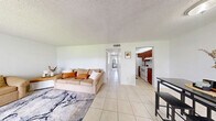 Located in North Lauderdale, FL, this single-floor, two-bedroom, one-bathroom unit offers a functional and well-organized layout. The living room greets you with light tile flooring, a textured ceiling, and multiple windows dressed with vertical blinds that allow natural light to fill the space, creating a bright and open atmosphere.

The galley-style kitchen is a standout feature, lined on both sides with rich, warm-toned wood cabinetry and dark granite-style countertops. It is equipped with a full suite of white appliances, including a refrigerator, electric range, and dishwasher, making efficient use of the corridor layout.

Both bedrooms are carpeted and offer a comfortable, quiet retreat. The primary bedroom is generously sized and includes a large closet with louvered bifold doors, while the second bedroom also features a closet and neutral tones, making it well-suited as a guest room or home office.

The shared full bathroom includes a combined tub and shower with tile surrounds, a wood-toned vanity with countertop storage, and tile flooring that continues the cohesive design found throughout the unit. A hallway connects the main living areas to the bedrooms and bathroom, keeping the layout practical and easy to navigate. Overall, the unit presents a clean, functional, and comfortable living space.