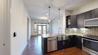 Located at 4139 Bellaire Blvd in the desirable Southside Place community of Houston, TX, this 1-bedroom, 1-bathroom residence offers a thoughtfully designed single-floor layout with upscale finishes throughout. The open-concept kitchen and dining area serves as the heart of the home, showcasing dark espresso cabinetry, granite countertops, a striking exposed brick backsplash, and a central island with a stainless steel farmhouse sink. Pendant lighting adds a modern touch overhead, while stainless steel appliances, including a gas range, built-in microwave, and refrigerator, complete the kitchen. Rich hardwood flooring flows throughout the main living areas, leading to a bright living space featuring French doors that open to a private balcony, flanked by large windows that invite abundant natural light. The bedroom offers plush carpet flooring, a ceiling fan, and a dedicated walk-in closet with built-in shelving. The bathroom is elegantly appointed with large-format tile flooring, dark cabinetry with granite countertops, and a glass-enclosed walk-in shower with floor-to-ceiling tile surround. Ceiling fans in key rooms and recessed lighting throughout add comfort and practicality to this refined urban residence.