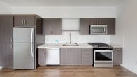 Located on the seventh floor at 1110 F Street in San Diego, Unit #706 is a contemporary residence designed with clean lines and modern finishes throughout. The open layout is anchored by a stylish kitchen featuring dark wood-grain cabinetry, light quartz countertops, a white subway tile backsplash, and a full suite of stainless steel appliances including a gas range, built-in microwave, dishwasher, and refrigerator. Durable wood-look flooring runs through the kitchen and main living areas, lending warmth and continuity to the space. The bedrooms are carpeted for comfort and offer generous proportions, with large windows that frame city views and fill the rooms with natural light. Each bedroom provides ample closet space, including a mirrored sliding-door closet in the primary suite. Two bathrooms serve the unit: one featuring a dark-toned vanity with quartz countertop and hardwood-style flooring, and a second with a full tub-and-shower combination, white tile surround, and a sleek vanity. A dedicated entryway near the front door houses a stacked in-unit washer and dryer, adding everyday convenience. The overall aesthetic is bright, clean, and move-in ready, reflecting a thoughtful modern design throughout.