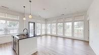 This well-designed 2-bedroom, 2-bathroom residence offers a thoughtfully laid-out single-floor plan with modern finishes throughout. The open-concept kitchen is a standout feature, equipped with white shaker cabinetry, subway tile backsplash, dark granite countertops, stainless steel appliances, and a central island with pendant lighting overhead — ideal for both cooking and entertaining. Light wood-look flooring flows consistently throughout the entire residence, creating a clean, cohesive aesthetic.

The living area is bathed in natural light courtesy of an impressive bank of large windows that span nearly an entire wall, offering generous outdoor views and an airy, open ambiance. Both bedrooms are comfortably proportioned, with large windows, ceiling fans, and stylish three-panel gray interior doors. Each bedroom benefits from dedicated closet space, including a walk-in closet with built-in shelving in the primary bedroom.

The two bathrooms are finished to a high standard, featuring granite-topped vanities, wood-look flooring, matte black fixtures, and framed mirrors. The primary bathroom includes a glass-panel walk-in shower, while the second bathroom offers a full tub-shower combination with white tile surround. Two additional closets provide practical storage throughout the residence.