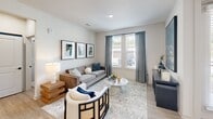 Located in Lafayette, Louisiana, this well-designed 2-bedroom, 2-bathroom single-floor residence offers a thoughtful layout with modern finishes throughout. Light wood-look flooring flows consistently across the space, tying each room together with a clean, contemporary aesthetic.

The kitchen is a standout feature, showcasing white upper cabinetry, soft gray lower cabinets, a herringbone-patterned tile backsplash, and quartz countertops. A center island with seating provides additional prep and dining space, while stainless steel appliances and sleek black pendant lighting complete the polished look.

The living room receives generous natural light through large windows dressed with gray drapes, creating a bright and welcoming atmosphere. The hallway entry is well-appointed, with recessed lighting and direct sightlines into the kitchen.

Both bedrooms are comfortably proportioned, each featuring ceiling fans, large windows with outdoor views, and neutral wall tones. The primary bedroom offers a serene retreat with ample natural light.

The two bathrooms are finished to a high standard. One features a marble-tiled walk-in glass shower, white vanity with undermount sink, and wood-look flooring. The second includes a marble-surround tub/shower combo and matching white cabinetry. Both bathrooms incorporate matte black hardware accents for a modern touch.