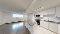 Located at 2233-2235 Hurontario Street in Mississauga, this well-appointed one-bedroom, one-bathroom unit offers a thoughtfully designed layout across a single floor. The open-concept living and dining area is bright and airy, bathed in natural light from large floor-to-ceiling windows that frame outdoor views and connect to a private balcony. Classic parquet hardwood flooring runs throughout the main living spaces, adding warmth and character to the clean, white interior palette.

The modern kitchen is a standout feature, finished with crisp white cabinetry, subway tile backsplash, stainless steel appliances including a range, built-in microwave, dishwasher, and refrigerator, as well as a peninsula with a dark countertop that provides additional workspace and a natural divide between the kitchen and living areas. Light tile flooring completes the kitchen's fresh, contemporary look.

The bedroom is a comfortable size, featuring mirrored sliding closet doors and parquet flooring, with a window offering natural light. Three closets throughout the unit provide generous storage. The bathroom is finished with classic white subway tile surrounding a full soaking tub with an integrated shower. An entrance hallway and additional storage areas complete this functional and well-organized home.