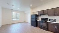 Located at 2312 F Ave in National City, CA, this thoughtfully designed two-bedroom, one-bathroom residence offers a clean, modern aesthetic across a single floor. Light wood-tone flooring runs throughout the space, creating a warm and cohesive look that ties each room together seamlessly.

The kitchen is a standout feature, appointed with rich dark espresso cabinetry, light quartz countertops, and black appliances including a full-size refrigerator, electric range, built-in microwave, and dishwasher. Recessed lighting overhead adds a polished finish to this functional and stylish cooking space.

The bedrooms are bright and airy, benefiting from multiple windows that invite natural light and offer views of the surrounding greenery. The primary bedroom provides a comfortable sense of space, complete with a sliding double-door closet for ample storage. The second bedroom mirrors the same clean, light-filled character.

The bathroom is finished in a crisp, all-white palette, featuring a shower-tub combination with subway tile surround, modern chrome fixtures, a dark wood vanity with a light countertop, and the same wood-tone flooring found throughout the home.

Overall, the residence presents a bright, minimalist atmosphere with consistent modern finishes, making it a well-appointed and practical living space.