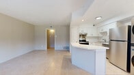 This single-floor, 3-bedroom, 2-bathroom home offers a thoughtfully designed layout that maximizes every square foot. The open-concept living and kitchen area serves as the heart of the home, with large-format neutral tile flooring flowing seamlessly throughout. The kitchen is outfitted with crisp white shaker-style cabinetry, a classic subway tile backsplash, stainless steel appliances including a range and refrigerator, and a white quartz peninsula that provides additional prep and seating space. A stacked washer and dryer unit is conveniently integrated into the kitchen area, adding in-unit laundry functionality. The living room is bright and open, with neutral walls and easy access to the hallways leading to the bedrooms. The primary bedroom offers a comfortable footprint with a ceiling fan and a closet. The additional bedrooms are well-sized, each featuring tile flooring, ceiling fans, and windows that bring in natural light. Both bathrooms are finished with wood-look tile flooring, gray vanity cabinetry, white quartz countertops, and brushed nickel fixtures. One bathroom features a tub-shower combo with floor-to-ceiling gray tile surround, while the second includes a white subway-tiled shower. The overall aesthetic is clean, modern, and move-in ready.
