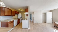 Located at 9189 Gale Blvd in Thornton, Colorado, this 2-bedroom, 1-bathroom unit offers a practical and comfortable single-floor layout. The living room is bright and welcoming, featuring light hardwood-style flooring, neutral beige walls, a textured ceiling, and a large window with vertical blinds that allow generous natural light to fill the space. A baseboard heating system is present throughout the unit for efficient warmth.

The galley-style kitchen is well-appointed with warm wood cabinetry, granite-look countertops, and white appliances including a range, refrigerator, and dishwasher. A washer and dryer are also accommodated within the kitchen corridor, adding everyday convenience.

Both bedrooms are carpeted and offer a cozy, quiet atmosphere. The primary bedroom is generously sized, featuring a large window with natural light, a built-in closet with double doors, and baseboard heating. The second bedroom is similarly finished with carpet, a window with outdoor views, and its own closet access.

The full bathroom is clean and functional, featuring a granite-look vanity with a wood cabinet base, a tiled tub-shower combination, and wood-style flooring. The unit also includes a hallway and dedicated closet for additional storage. Overall, the space presents a cohesive, neutral aesthetic throughout.
