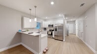 Located at 101 Haven Blvd in Palm Coast, Florida, this single-story, 3-bedroom, 3-bathroom home offers a clean, modern aesthetic throughout. Light wood-tone flooring flows consistently across all rooms, complemented by soft gray walls and crisp white trim and doors, creating a bright and cohesive interior palette.

The open-concept living, dining, and kitchen area serves as the heart of the home. The kitchen is well-appointed with white shaker-style cabinetry, white countertops, stainless steel appliances including a French door refrigerator, electric range, and microwave, and a peninsula with pendant lighting that provides additional prep and seating space.

The three bedrooms are comfortably sized, with the primary bedroom featuring an en-suite bathroom equipped with a frameless glass walk-in shower and brushed nickel fixtures, as well as direct access to a private outdoor area via sliding glass doors. The additional bedrooms include windows that bring in natural light and ceiling fans for comfort. The home includes five closets in total, providing generous storage throughout.

Three full bathrooms are finished with clean, white interiors and light wood flooring. A dedicated laundry room and a hallway connecting all major rooms round out the functional layout of this well-designed Florida home.