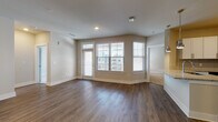 Located at Annabelle on Main in Duluth, GA, this 2-bedroom, 2-bathroom residence is designed with contemporary finishes and a functional, open-concept layout. The living area features rich hardwood-style flooring and neutral toned walls, filled with natural light from multiple windows with views of the surrounding community. A ceiling fan adds comfort to this welcoming space, which flows seamlessly into the dining and kitchen areas.

The kitchen is a standout feature, showcasing crisp white shaker cabinetry, granite countertops, a subway tile backsplash, and a full suite of stainless steel appliances including a range, microwave, dishwasher, and refrigerator. A kitchen island with a undermount sink provides additional prep space and casual dining options, complemented by stylish pendant lighting.

Both bedrooms are generously sized with plush wall-to-wall carpeting, large windows, and ample closet space, including a spacious walk-in closet with wire shelving systems. The bathrooms are finished with white cabinetry, granite-topped vanities, brushed nickel hardware, and a tub-shower combination with wood-look flooring. A dedicated in-unit laundry room accommodates a full-size washer and dryer with overhead wire shelving for added storage convenience.