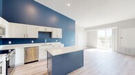 Located at 818 Fourth St NW in Faribault, Minnesota, this well-designed two-bedroom, two-bathroom single-floor residence offers a thoughtful layout with modern finishes throughout. The standout feature is the kitchen, where bold blue accent walls contrast beautifully against white cabinetry, light quartz countertops, and stainless steel appliances, including a refrigerator, range, microwave, and dishwasher. A center island provides additional prep space and anchors the open connection to the living area. Light wood-look flooring runs throughout the main living spaces, lending warmth and continuity. The primary bedroom is generously sized, filled with natural light from large windows that offer neighborhood views, and features plush carpeting underfoot. Both bedrooms are served by walk-in closets outfitted with wire shelving systems, providing ample storage. The two bathrooms are clean and functional, each featuring a walk-in shower with white surround, light wood-look flooring, and matte black hardware accents. A dedicated in-unit laundry room houses a full-size washer and dryer. A central hallway connects all areas efficiently. The overall aesthetic is fresh, modern, and move-in ready.