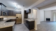 Located at 8531 Summersweet Ln in Raleigh, NC, this single-floor residence offers a well-designed layout with contemporary finishes throughout. The kitchen is a standout feature, showcasing dark espresso cabinetry, granite countertops, a tile backsplash, and a full suite of stainless steel appliances including a refrigerator with ice maker, electric range, over-the-range microwave, and dishwasher. A peninsula provides additional prep space and opens toward the main living areas, which are finished with durable wood-look flooring. The living room is highlighted by a fireplace, ceiling fan, and a sliding glass door that brings in natural light and outdoor views. Built-in shelving adds a functional design detail to the dining or flex area. Bedrooms are carpeted and generously sized, with large windows dressed in blinds that frame views of surrounding greenery. The primary bathroom features a dual-sink vanity with granite countertops, dark cabinetry, and a large mirror, while a secondary bathroom offers a similar aesthetic on a smaller scale. The primary suite also includes a spacious walk-in closet with wire shelving. Throughout the home, neutral tones and consistent finishes create a cohesive, modern ambiance.